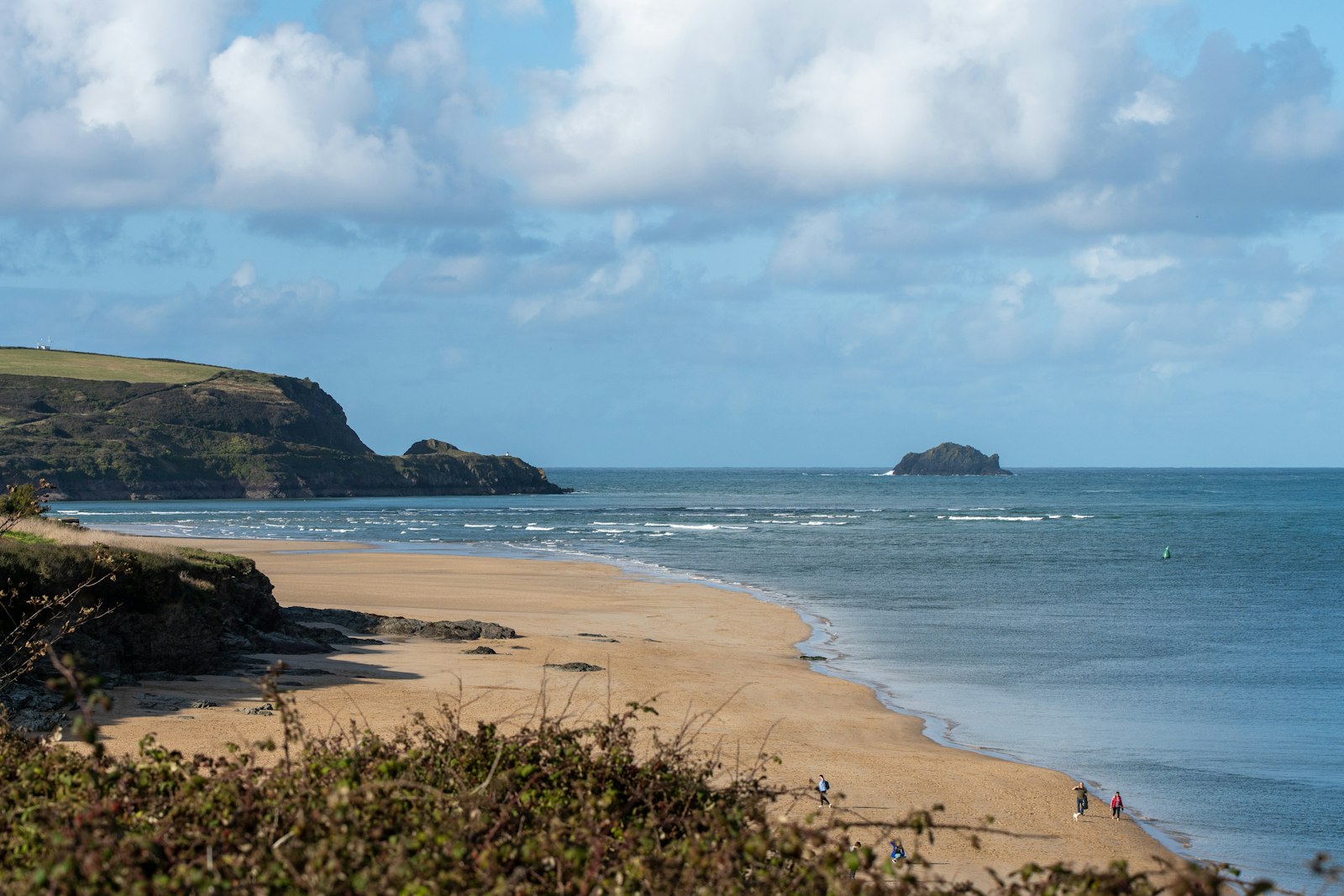 A Cornish beach and headland under a wide sky