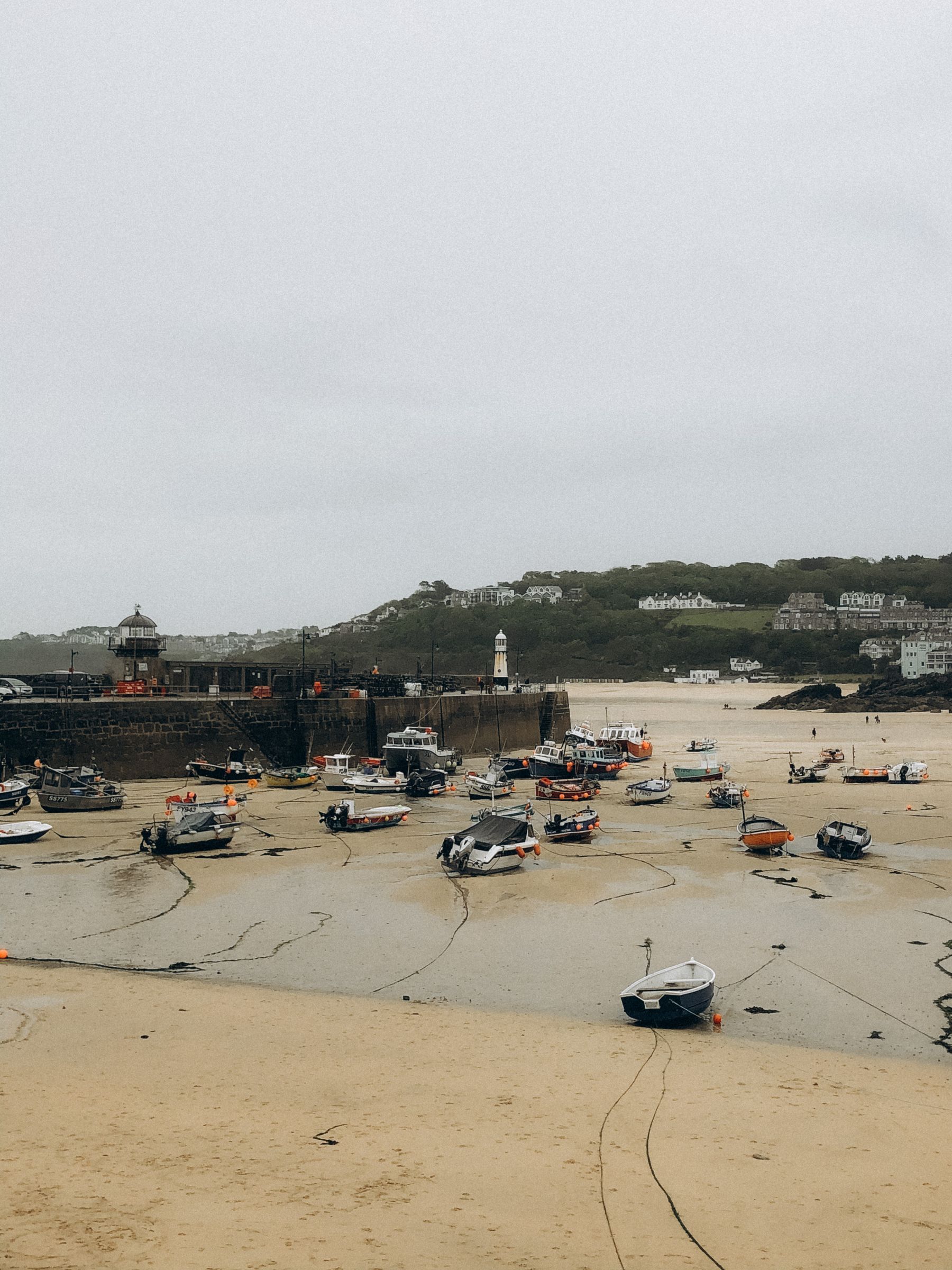 St Ives harbour at low tide, boats resting on the sand beneath the lighthouse